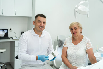 Male dentist talking with senior patient about future treatment. Healthcare concept