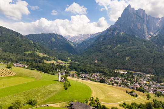 St. Valentin church surrounded by meadows and fields, with Schlern massif in background, Castelrotto in Dolomites Alps. South Tyrol, Italy