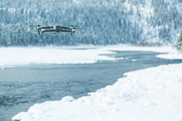 Flying drone against winter background with river and forest