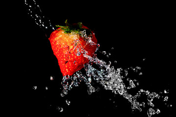 Macro shot of strawberry with water splash on black background