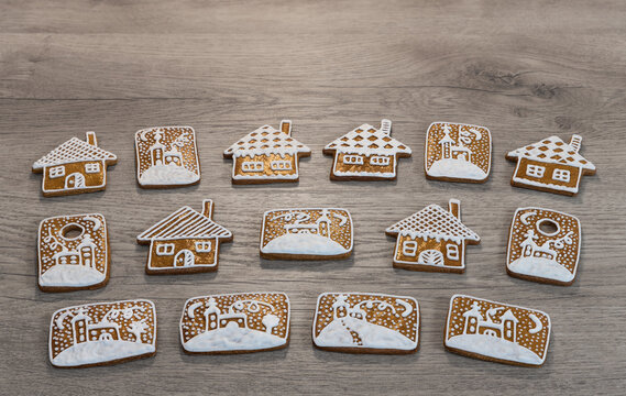 Set of Xmas gingerbread houses and churches with winter snow decoration on wooden background. Close-up beautiful golden baked Christmas and New Year pastries decorated by sweet white frosting. Advent.
