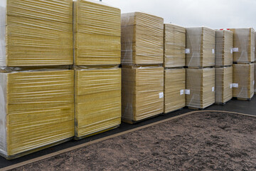 Stacked insulation boards wrapped on pallets at construction site for industrial building project