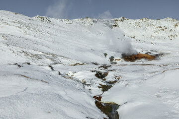 Geothermal steam rising in snowy Reykjadalur Valley, Iceland.