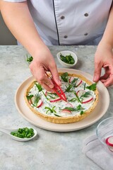 Step-by-step preparation of a savory shortcrust pastry tart filled with cottage cheese, cream cheese, herbs, and fresh vegetables against a gray concrete background.
