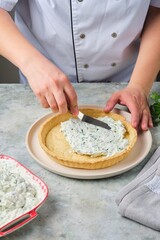 Step-by-step preparation of a savory shortcrust pastry tart filled with cottage cheese, cream cheese, herbs, and fresh vegetables against a gray concrete background.