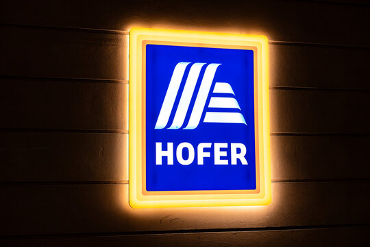Vienna, Austria - 15 December, 2025: A brightly lit Hofer supermarket sign in Vienna, Austria. The sign features a blue background with white lettering and a distinctive logo.