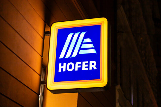 Vienna, Austria - 15 December, 2025: A brightly lit Hofer supermarket sign in Vienna, Austria. The sign features a blue background with white lettering and a distinctive logo.
