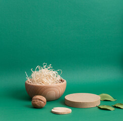 Minimal boho product podium with natural decoration - wooden bowl, walnut, wooden circle, leaves on a deep green background