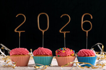 Holiday cupcake with pink glaze and 2026 numbers on black background. New Year and Christmas.