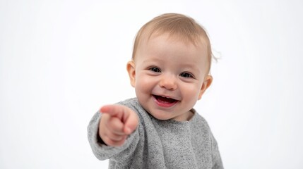 Happy baby pointing finger forward, looking directly at camera with a joyful expression, wearing a gray top on a clean white background, creating a positive concept