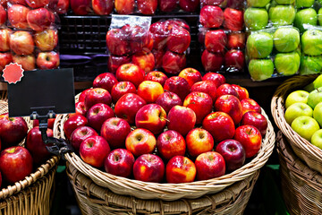 Organic market. Fresh red apples are arranged in woven basket, showcasing their glossy skin and vibrant colors, surrounded by green apples in lively market display, highlighting abundance of produce