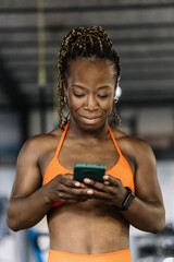 Woman smiling reading messages on smartphone in gym