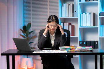 Stressed at the Desk: A focused woman sits at her desk, visibly stressed as she contemplates her...