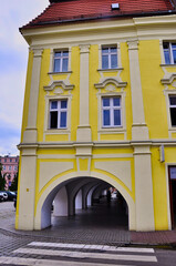 Żółty, zabytkowy budynek z arkadowym łukiem na ulicy miejskiej, z ozdobnymi oknami. Miasto Jawor - Rynek w zabytkowym Starym Mieście. © Pol Badger