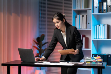 Focused Professional at Work: A poised business professional, diligently working on her laptop at a...