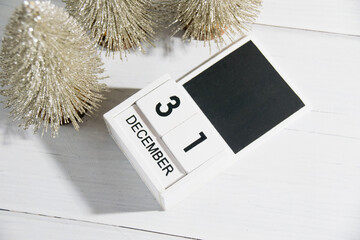 Decorative Christmas trees on a gray background and a wooden calendar with the date December 31