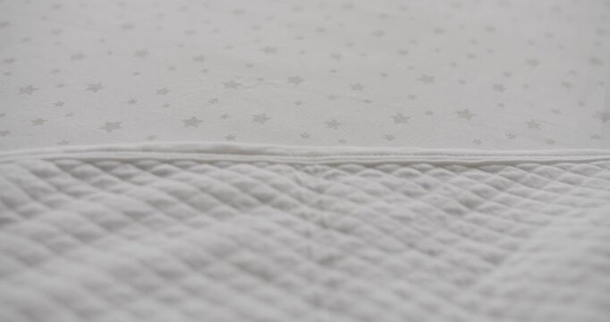 Modern empty wooden crib with mattress, cotton sheet and blanket in nursery room. Preparing baby bed for newborn comfort sleep. Wooden crib with mattress, cotton sheet and blanket in nursery room.