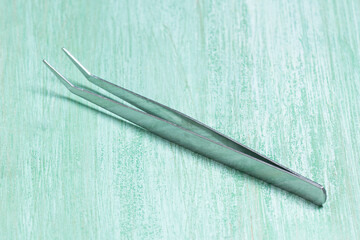 Curved Metal Tweezers on Mint Green Wood