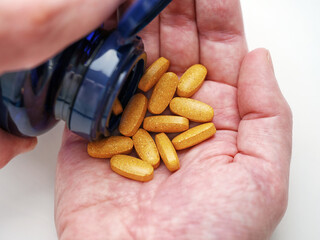 A man taking Vitamin B Complex tablets out of a bottle. Close up.