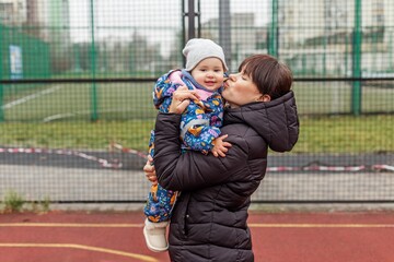 Mother kissing happy baby in winter clothes