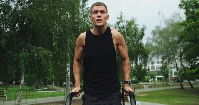 Athletic man has workout, hanging and pull up on parallel bars outdoors. Fitness and sport lifestyle. Sports, health care, fitness routine, workout. Strength, motivation. Outdoors gym.