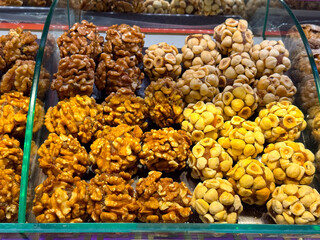 Nut and fruit based sweets arranged in compact clusters inside a display case in Istanbul bazaar. Traditional confectionery, natural energy foods, and artisanal craftsmanship presented through texture