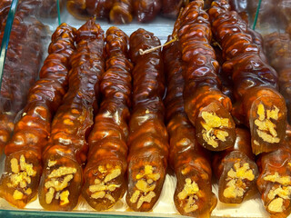 Amber colored churchkhela rolls filled with walnuts displayed closely together in Istanbul bazaar. Artisanal dessert making, traditional grape based sweets, and cultural food heritage expressed