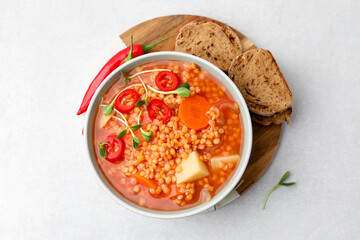 Delicious lentil soup with vegetables served on light grey table, top view