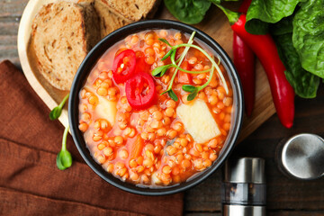 Delicious lentil soup with vegetables served on wooden table, flat lay