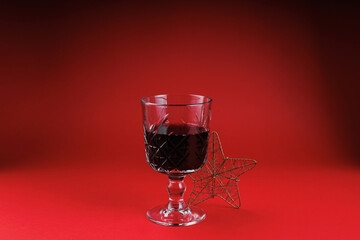 Red wine glass and golden wire star on red background reflecting festive elegance and symbolic mood