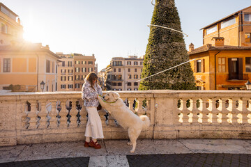 Woman spending a festive moment with her dog near a decorated Christmas tree in Rome by the Spanish Steps. Holiday atmosphere, winter tourism, New Year spirit, joyful travel and European lifestyle