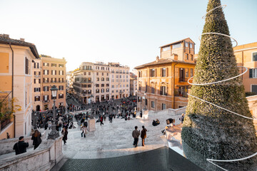 Festive winter atmosphere in Rome near the Spanish Steps with a decorated Christmas tree and lively city square. Holiday tourism, city break travel, celebration, joy and European urban lifestyle