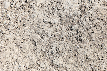 Dry gravel ground texture background. Rough sandy surface with small stones. Natural dirt pattern closeup. Earthy neutral tones. Outdoor soil texture for design use.