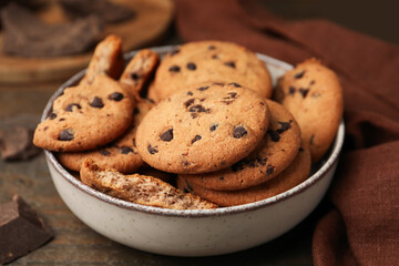 Yummy chocolate chip cookies in bowl on wooden table, closeup