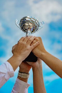 United hands raising trophy against blue sky