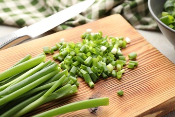 Cut green onions and knife on table, closeup