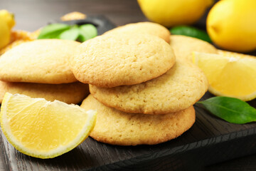 Tasty lemon cookies and fruit slices on dark wooden table, closeup
