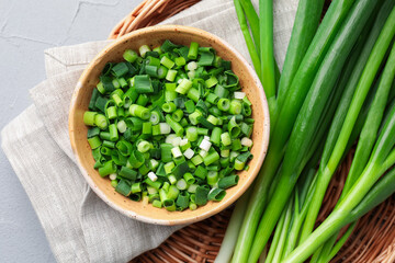 Whole and cut fresh green onions on grey table, top view
