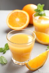 Fresh orange juice, mint and fruits on light table, closeup