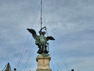 Rome, Italy - 12 January 2025. Bronze Archangel Michael statue crowns Castel Sant'Angelo, with support cables rising around it against an Overcast sky.