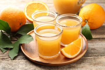 Fresh orange juice and fruits on wooden table, closeup
