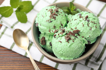Tasty mint chocolate chip ice cream, spoon and towel on wooden table, closeup