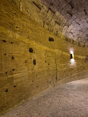Rome, Italy - 12 January 2025. Interior hallway of Castel Sant'Angelo with yellow-lit brick wall, arched ceiling, and rough stone floor showing age and repairs.