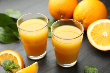 Fresh orange juice and fruits on black table, closeup