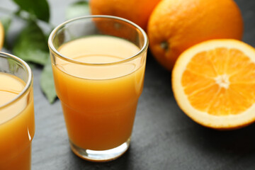 Fresh orange juice and fruits on black table, closeup