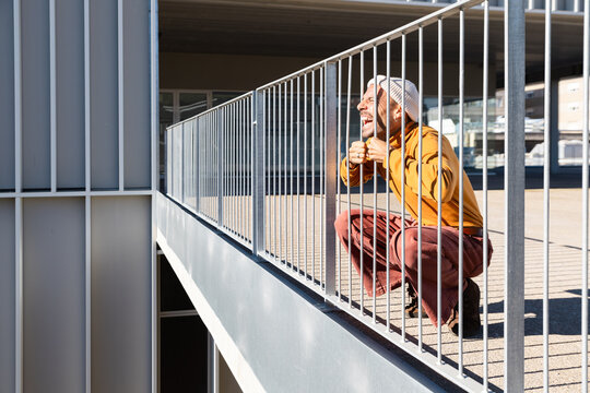 Person crouching playfully behind outdoor railing