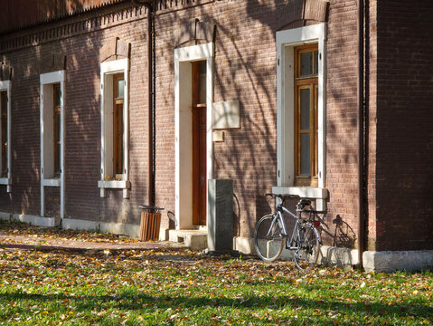 Bicycle resting against a brick building in autumn light