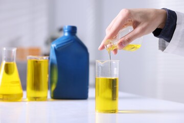 Scientist checking motor oil quality at table in laboratory, closeup