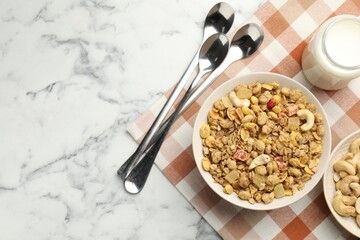 Tasty granola with dried fruits and nuts in bowl and milk on white marble table, flat lay. Space for text