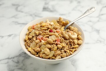 Tasty granola with dried fruits and nuts in bowl on white marble table, closeup